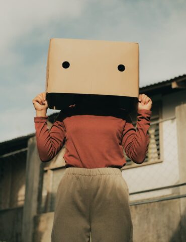 anonymous woman with box on head near building